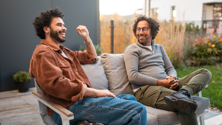 Two people smiling on the back deck in an open backyard