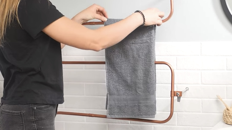 person hanging towel on copper pipe rack