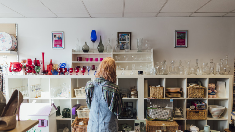 Woman browsing the glassware section of a thrift store