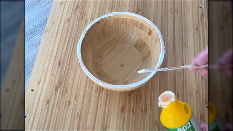 Woman assembling bamboo wood IKEA bowl legs on DIY coffee table over wood floor