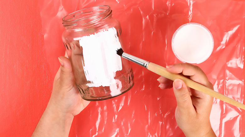 hands painting pickle jar