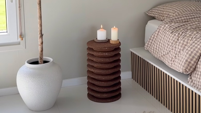 A DIY side table made from IKEA cork trivets sits between a potted plant and a bed