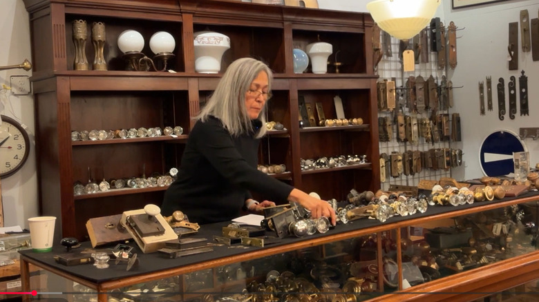 Woman behind counter with old door knobs on display