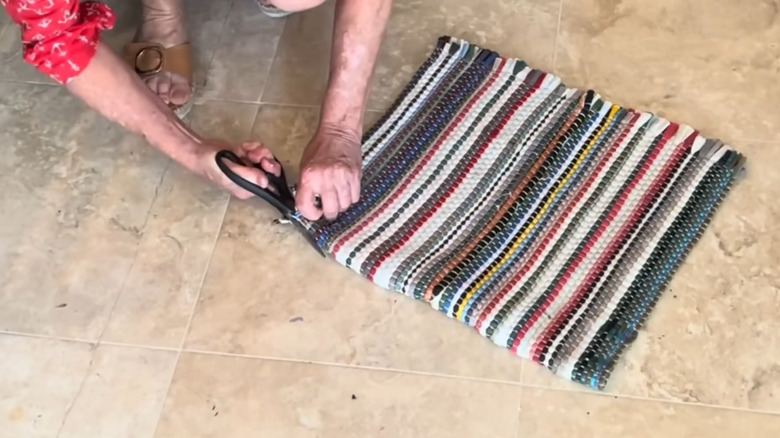 Creator cutting a rag rug in half to prepare it for a craft project