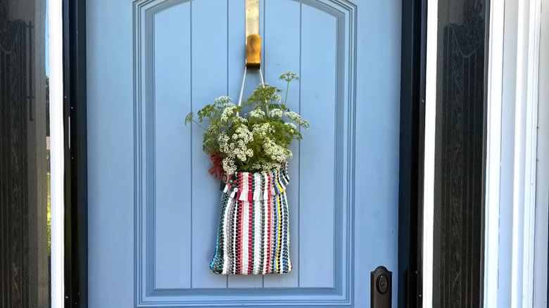 Flower holder made from a rag rug hanging on a front door