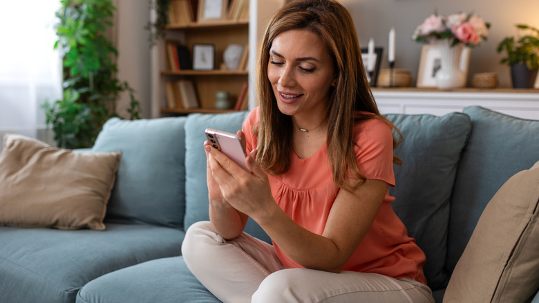woman sitting on sofa in living room looking at her phone