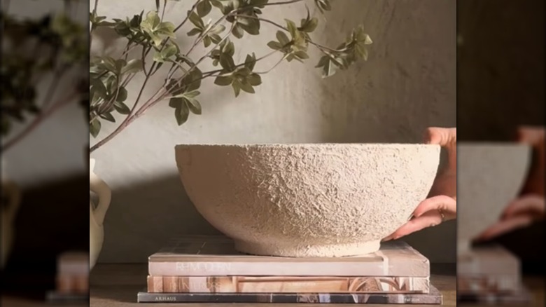 Faux stone bowl made by applying paint mixed with baking soda sitting on top of a stack of books