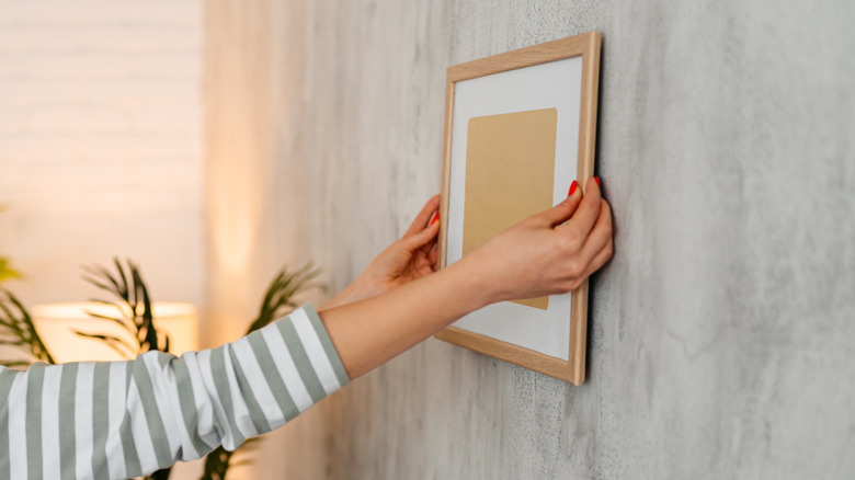 Woman putting empty picture frame on wall