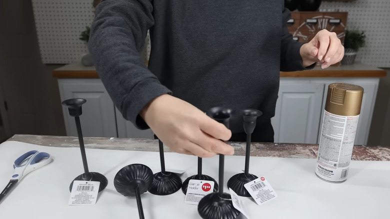 Creator arranging Dollar Tree candle holders to spray paint them