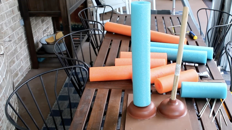 Plungers and cut up pool noodles on a table.