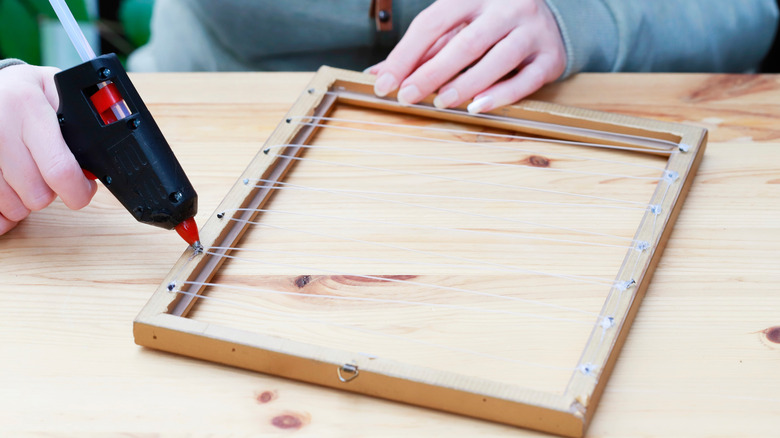 hand holding glue gun and picture frame
