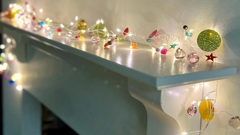 A one-of-a-kind fairy light strand decorated with leftover craft supplies illuminates a mantle