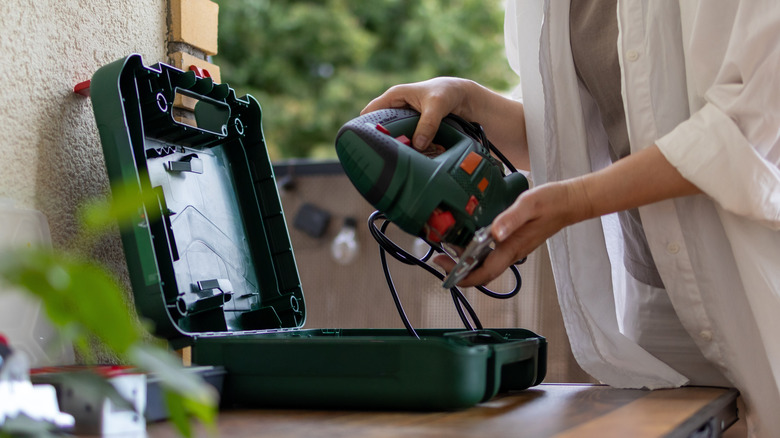 Woman taking out a jigsaw to cut scrap wood to size