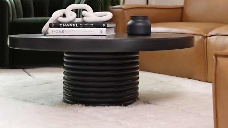 DIY coffee table made of wood rounds and painted black in a living room on a white rug