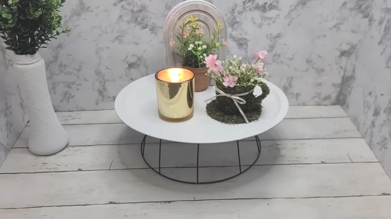 DIY dollar store countertop riser on white wood table with farmhouse-style vases and holden candle with marbled backdrop