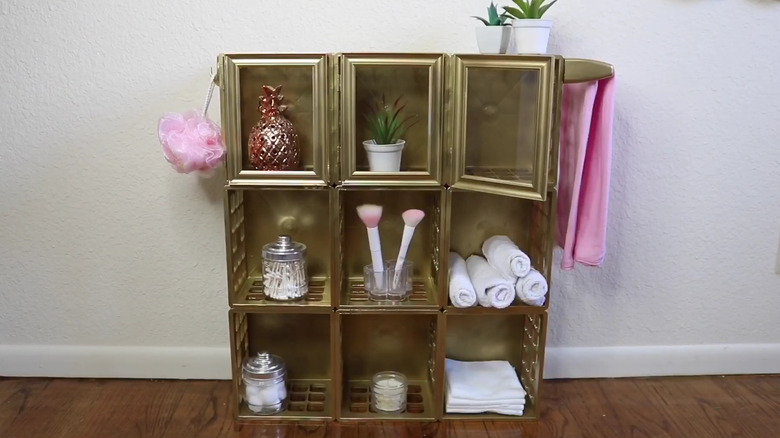 Golden bathroom shelf made from plastic crates with glass door fronts