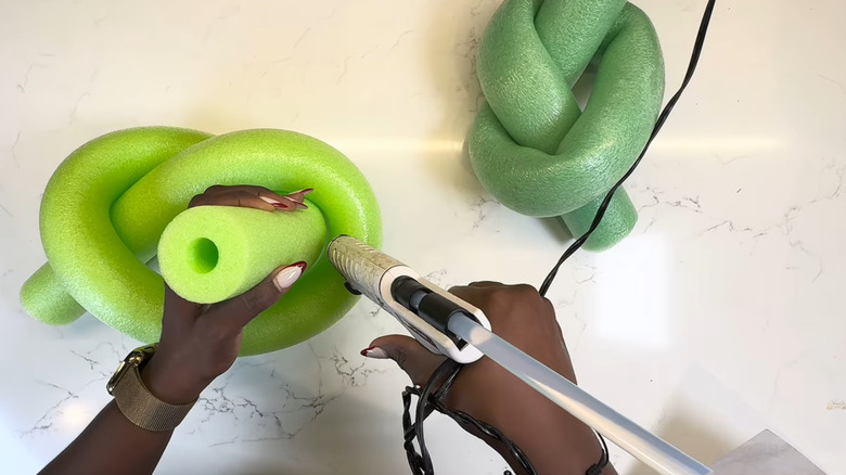 Woman works on a DIY project with green pool noodles