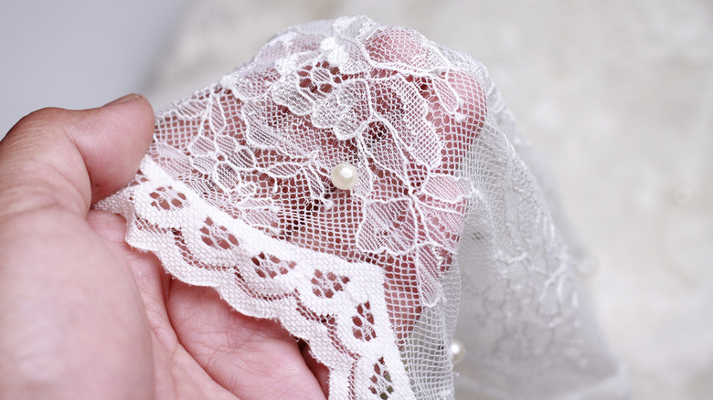 A hand holding lace fabric