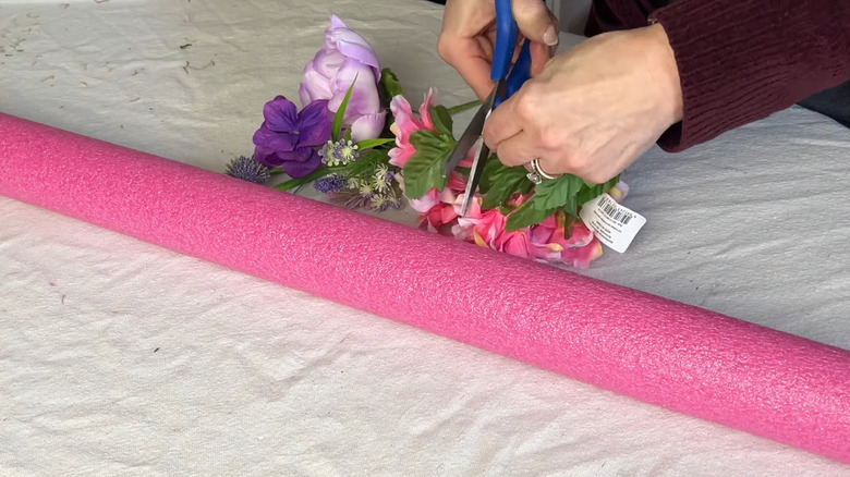 Woman cutting fake florals next to a pool noodle