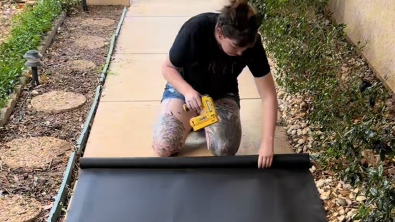 TikTok creator stapling black solar screen to wooden frame