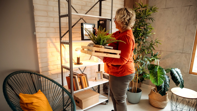 A woman styling a freestanding shelf in a living room
