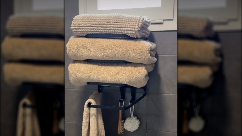 Stacked towels on wall-mounted bathroom rack made from IKEA baking sheet rack