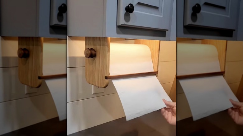 Wooden, one-handed paper towel holder suspended above a kitchen counter