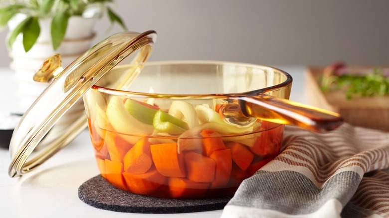 An orange Corning Visions pot with chopped vegetables inside