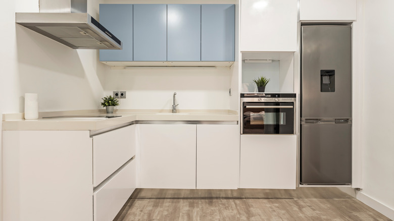 Plain-fronted, melamine-covered cabinets in a white kitchen