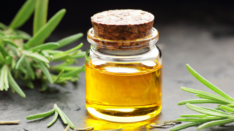 a bottle of rosemary oil surrounded by rosemary leaves