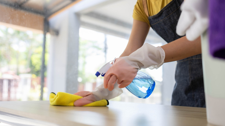 A woman spraying and wiping a kitchen counter