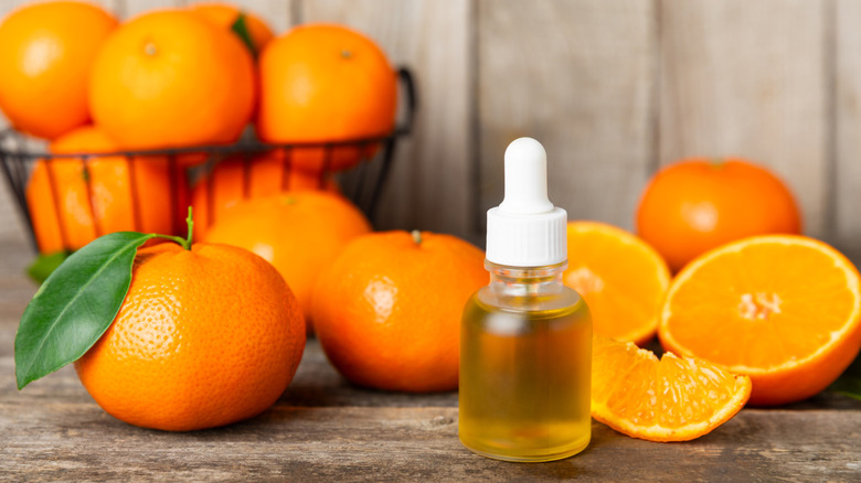 Bottle of essential oil in front of tangerines