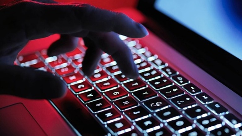 A hand typing on a backlit keyboard