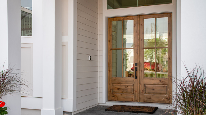 A large wooden front door with glass panels