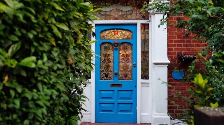 Blue front door with stained glass windows next to white pillar