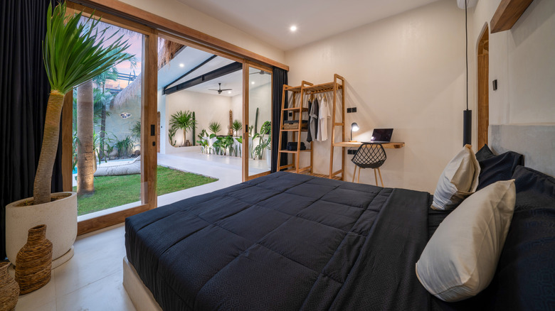 room with black bedding and large glass door open to patio