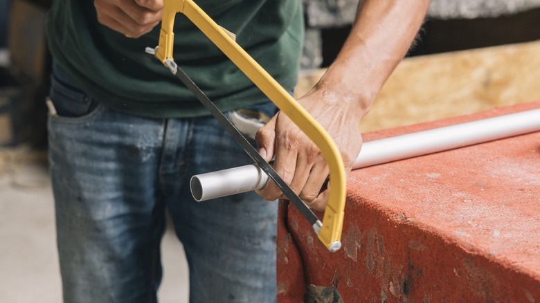 Person using a hacksaw to cut metal