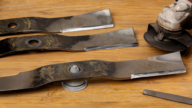 A closeup of three lawn mower blades before sharpening