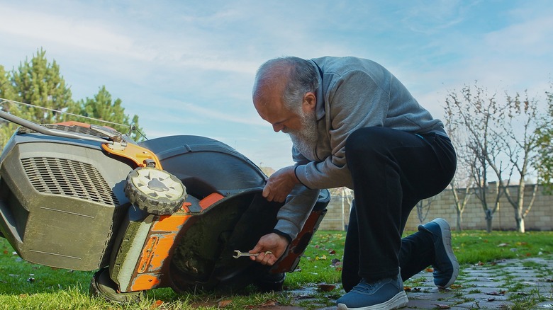 Older man removing lawn mower blade with a wrench