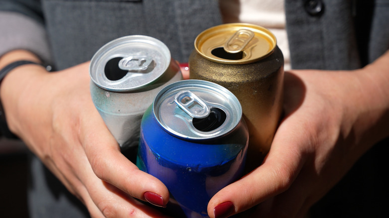 hands holding empty aluminum cans